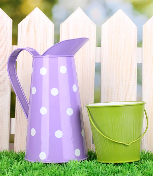 Gardening tools on green grass on wooden fence background — Stock Photo, Image