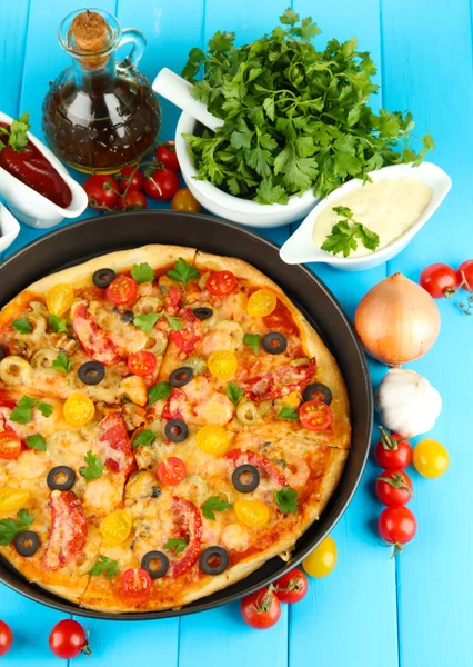 Färgglada sammansättning av läckra pizza, grönsaker och kryddor på blå trä bakgrund närbild — Stockfoto