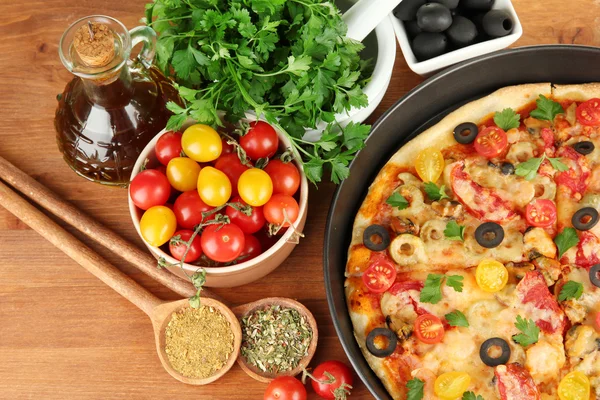 Colorful composition of delicious pizza, vegetables and spices on wooden background close-up — Stock Photo, Image