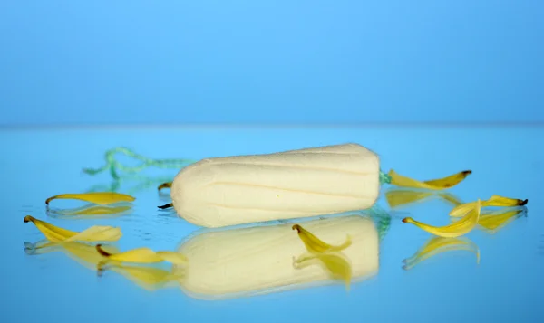 Assorbente in cotone con petali gialli su sfondo blu primo piano — Foto Stock