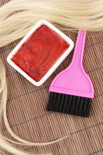 Tinte para el cabello en el tazón y el cepillo para la coloración del cabello en la estera de bambú marrón, primer plano — Foto de Stock