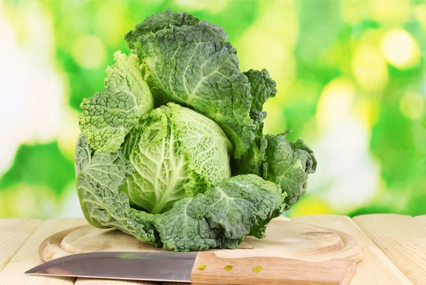 Fresh savoy cabbage on wooden table on natural background — Stockfoto