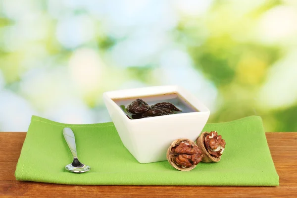 Jam walnuts in a bowl on a table on a green background — Stock Photo, Image