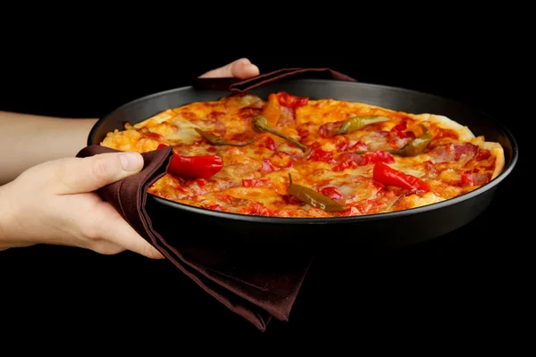 Mãos que mantêm a pizza de pepperoni na panela isolada no preto — Fotografia de Stock