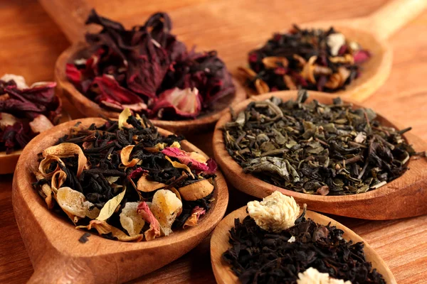 Assortiment van droge thee in lepels, op houten achtergrond — Stockfoto
