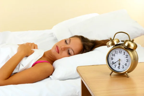ベッドと目覚まし時計の若い美しい女性 — ストック写真