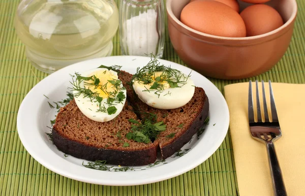 Gekookte eieren op donker brood op groene achtergrond — Stockfoto