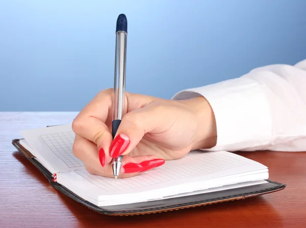 Ręczne podpisywanie w notesie na drewnianym stole na kolor tła — Zdjęcie stockowe