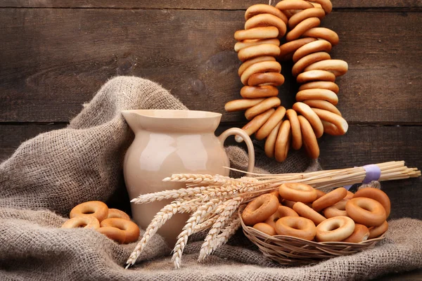 Jar of milk, tasty bagels and spikelets on wooden background — Stock Photo, Image