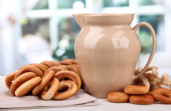 Pot van melk, smakelijke bagels en spikelets op tafel — Stockfoto