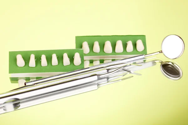 Set di strumenti dentali con dentiera su sfondo verde — Foto Stock