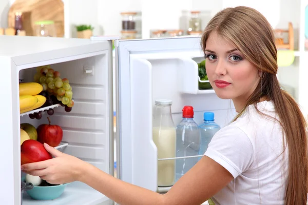 Young girl near refrigerator in kitchen — Stock Photo, Image