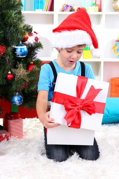 Kleine jongen open zijn gaven in de buurt van de kerstboom — Stockfoto