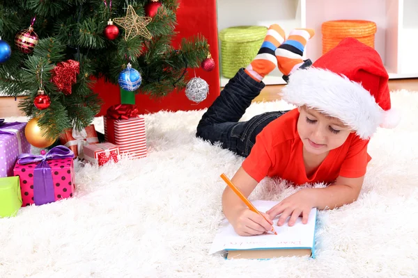 Kleine jongen in Kerstman hoed schrijft een brief aan de Kerstman — Stockfoto