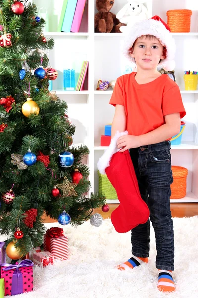 Menino no chapéu de Santa encontra seus presentes em meias vermelhas — Fotografia de Stock