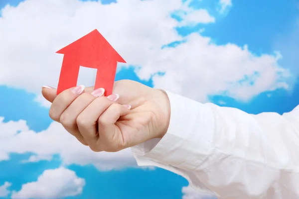 Concept: woman hand with paper house on sky background, close up — Stock Photo, Image