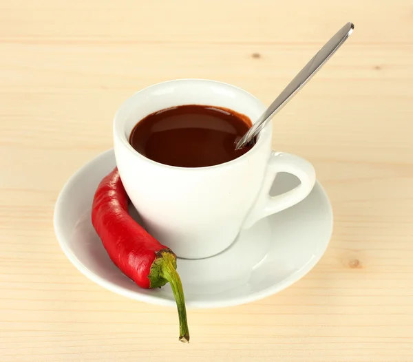 White cup with hot chocolate and chili pepper on wooden background Stock Photo