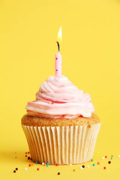 Tasty birthday cupcake with candle, on yellow background Royalty Free Stock Photos