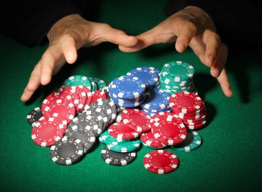 Poker fişleri ve yeşil masa üstündeki elleri