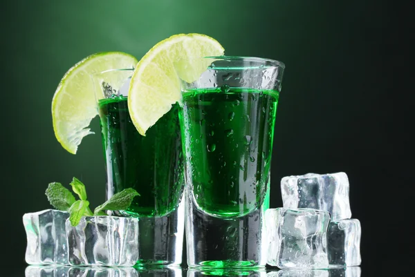 Deux verres d'absinthe, citron vert et glace sur fond vert — Photo