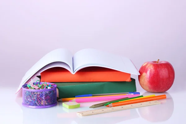 Komposition von Büchern, Papeterie und einem Apfel auf buntem Hintergrund — Stockfoto