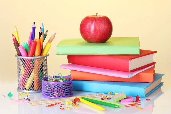 Komposition von Büchern, Papeterie und einem Apfel auf leuchtend buntem Hintergrund — Stockfoto