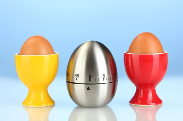 Zegar jaj oraz jaj w kolorze stoją na niebieskim tle — Zdjęcie stockowe