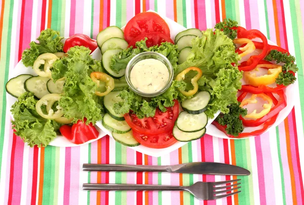 Подрібнені овочі та соус на тарілці на смугастій скатертині — стокове фото