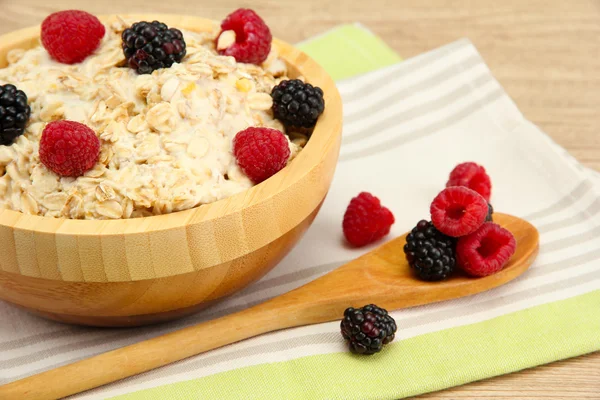 Tasty oatmeal with berries, on wooden table — Stock Photo, Image