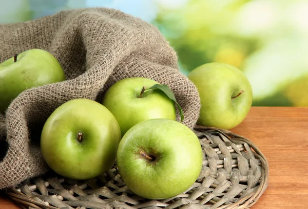 Çuval bezi, yeşil zemin üzerine ahşap masa üzerindeki yapraklarda ile olgun yeşil elma — Stok fotoğraf
