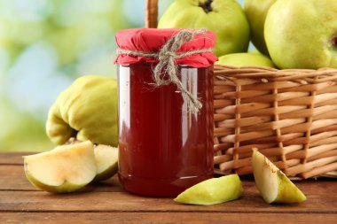 kavanoz reçel ve ayvaları ile sepeti, yeşil zemin üzerine bırakır.