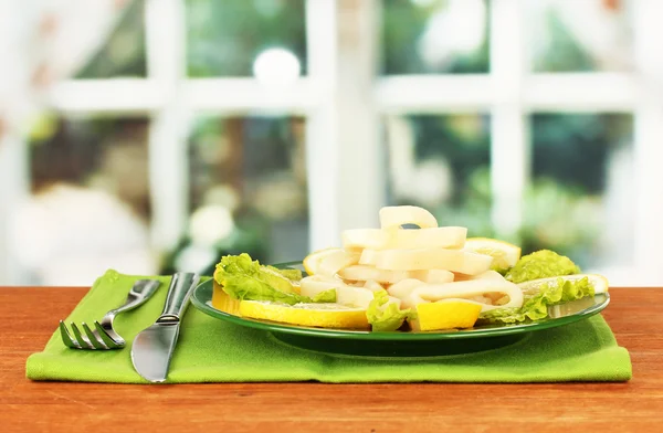 Anillos de calamar cocidos en lechuga con limón en el primer plano del plato — Foto de Stock