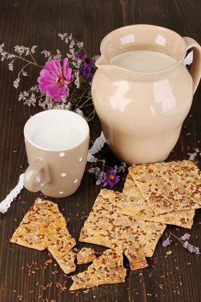 Pitcher and cup of milk with cookies on wooden table close-up — Stock Photo, Image