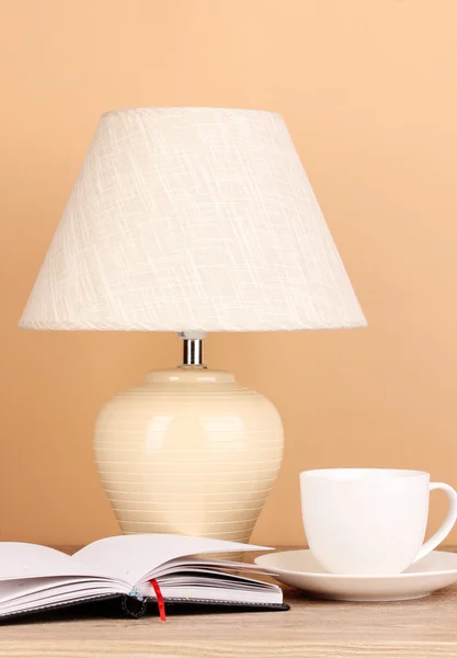 Table lamp and cup on beige background — Stock Photo, Image