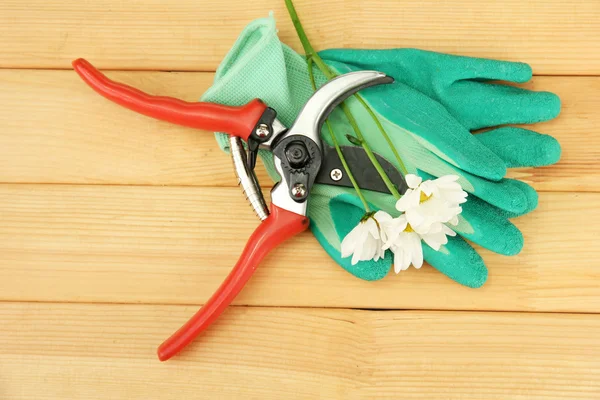 Secateurs with flower on wooden background — Stock Photo, Image