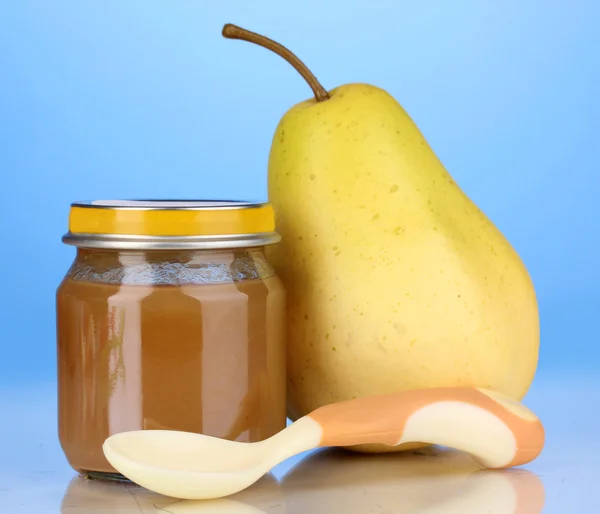 Useful and tasty baby food with pear and spoon on blue background — Stock Photo, Image