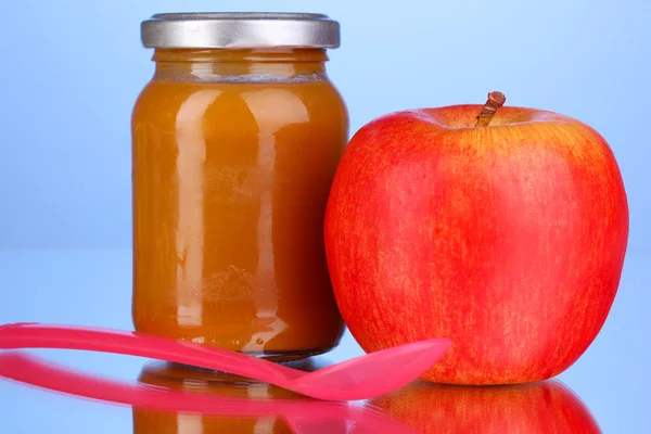 Nützliche und leckere Babynahrung mit Apfel und Löffel auf blauem Hintergrund — Stockfoto