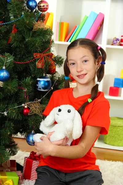 Little girl holding toy near christmas tree — Stock Photo, Image