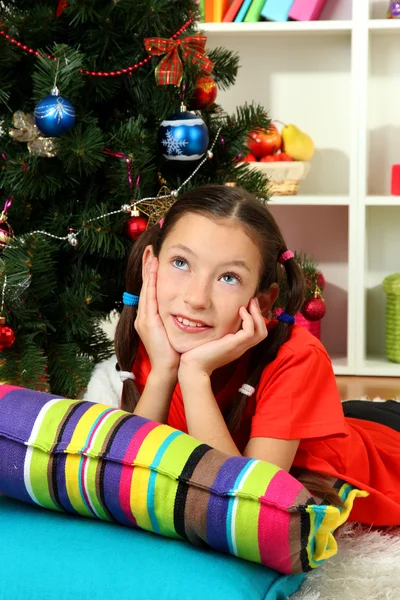 Kleines Mädchen träumt in der Nähe des Weihnachtsbaums — Stockfoto