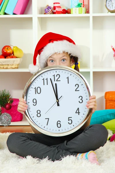 Little girl holding clock near christmas tree Stock Image