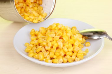 Mısır ve yeşil zemin üzerine ahşap masa kaşık konserve ve plaka açın