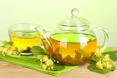 çaydanlık ve bardak ıhlamur çayı ve çiçeklerle yeşil zemin üzerine ahşap tablo