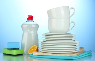 boş temiz tabak ve bardaklar bulaşık deterjanı, süngerler ve mavi zemin üzerine limon