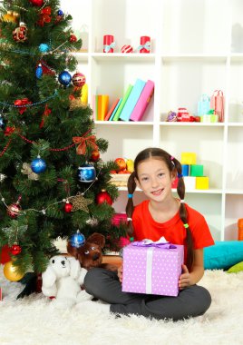 hediye kutusu Noel ağacının yakınında tutan küçük bir kız