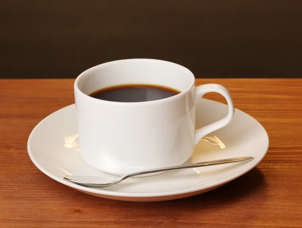Koffiekopje op houten tafel op bruine achtergrond — Stockfoto