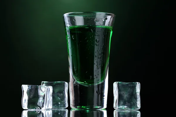 Glas Absinth und Eis auf grünem Hintergrund — Stockfoto