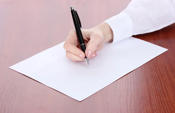 Woman hand writing on paper, on wooden table — Stock Photo, Image