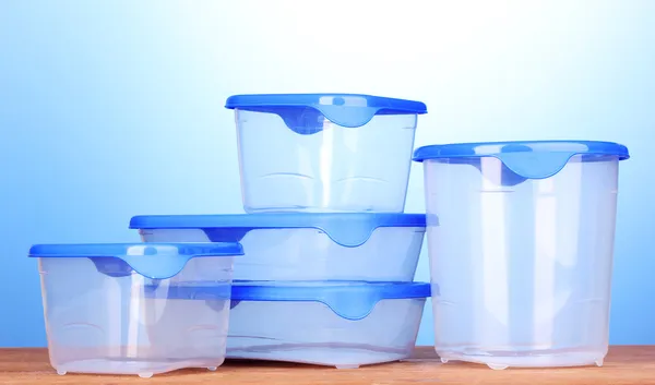 Plastic containers for food on wooden table on blue background — Stock Photo, Image