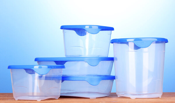 Пластиковые контейнеры для еды на деревянном столе на синем фоне
