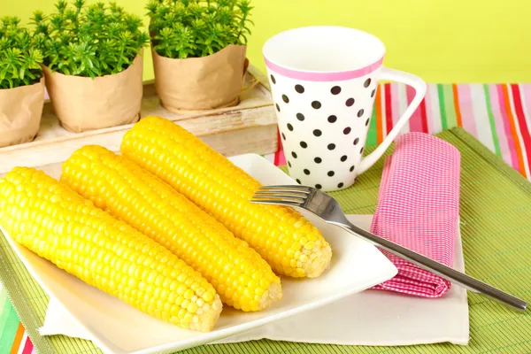 Boiled corn and a cup on a green background — Stock Photo, Image